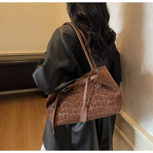 Chic leopard print brown suede tote bag carried by a model in a warm indoor setting