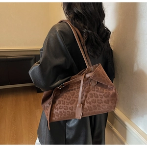 Detail of a leopard print suede tote bag styled with a leather jacket in a studio setting