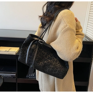 Close-up of black leopard print tote bag on shoulder featuring velvet texture and straps