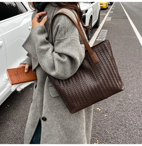 Detail of dark brown woven leather tote bag texture and smooth shoulder strap design