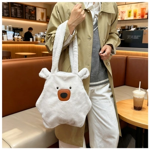 Detail of white plush polar bear shoulder bag worn by model in a cozy cafe setting