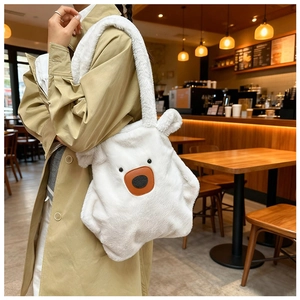 Detail of white plush polar bear shoulder bag with soft fur and brown leather nose accent
