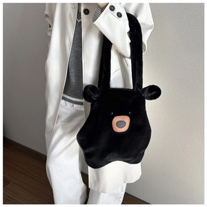 Detail of soft black plush bear-shaped tote bag with 3D ears on a white coat model