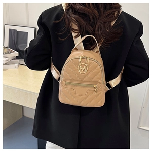 Detail view of khaki quilted PU leather mini backpack with golden M logo on a model
