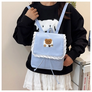 Detail of light blue mini backpack featuring lace trim and cute brown bear patch