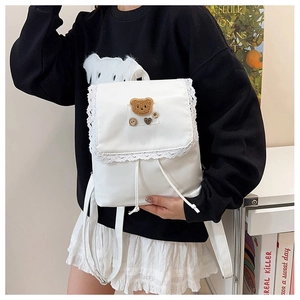 Dettaglio dello zaino in nylon bianco con pizzo e toppa a forma di orsetto