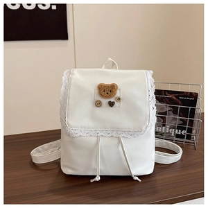Detailed side view of white lace backpack with cute brown plush bear patch and drawstrings