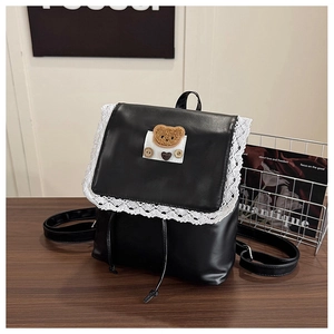 Détail d'un sac à dos noir en cuir PU avec dentelle blanche et écusson d'ours décoratif