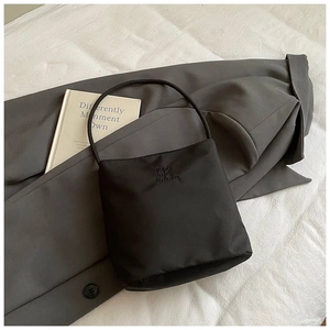Detalle del bolso de nailon negro con bordado Hope and future sobre una americana gris