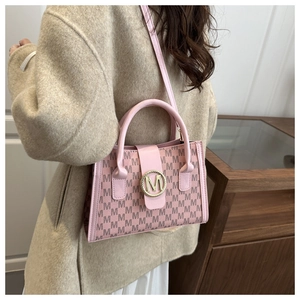 Detailed view of pink tote bag with embossed M-pattern and golden metal ring buckle