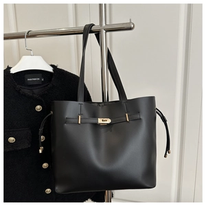 Gros plan d'un sac seau en cuir noir avec fermoir doré et détails de cordons latéraux