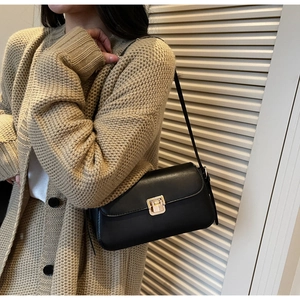 Dettaglio della borsa a tracolla in pelle nera minimalista con chiusura in metallo oro