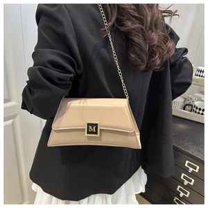 Detail showing the apricot leather crossbody bag with golden M logo and chain strap