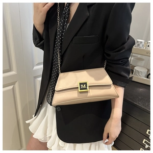Close-up of beige leather shoulder bag featuring a gold M-logo clasp and chain strap