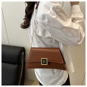 Brown leather underarm bag with gold M letter buckle and fine chain strap on model