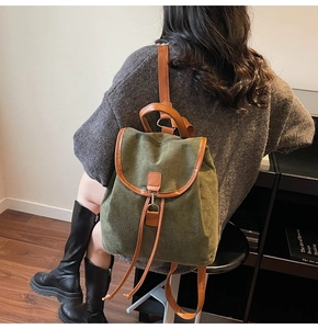 Détail d'un sac à dos en daim vert foncé avec garnitures en cuir brun et boucles