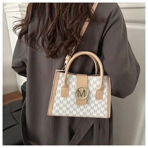 Detailed view of beige crossbody bag with M-pattern print and gold metal buckle
