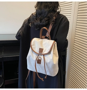 Détail du sac à dos en toile avec finitions cuir brun montrant le cordon de serrage