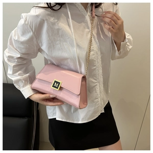 Detailed shot of pink faux leather crossbody bag featuring a golden M logo buckle and chain