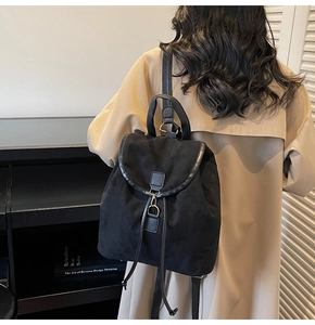 Vue détaillée du sac à dos en daim noir avec fermeture à cordon et garniture en cuir