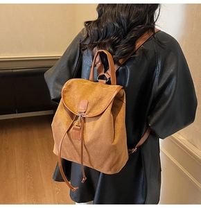 Détail du sac à dos en daim camel avec rabat, crochet métallique et fermeture à cordon