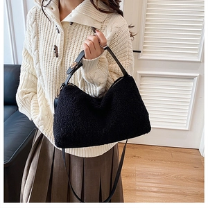 Close-up of black plush crossbody bag with gold hardware and faux sheepskin texture