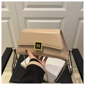 Detailed close-up of beige leather crossbody bag featuring gold M-letter metal buckle