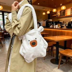 White faux fur plush tote bag with polar bear design shown on model in cafe setting