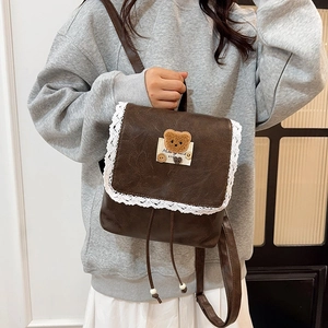 Mini sac à dos vintage marron avec bordure en dentelle et patch ours porté par un mannequin