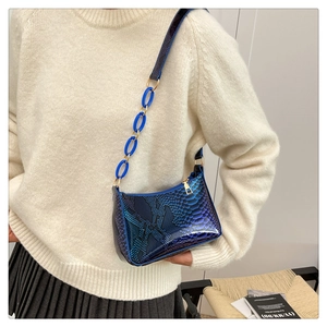 Detail of snake skin print baguette bag with chunky chain strap on a model shoulder
