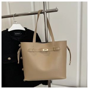 Détail du sac cabas kaki avec fermoir pivotant en métal, ceinture décorative et glands