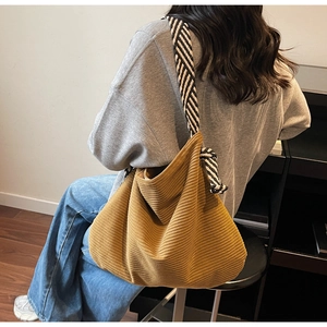 Detail of yellow corduroy tote bag with black and white striped woven shoulder strap