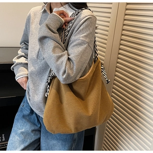 Detail of a ginger corduroy tote bag featuring unique black and white striped knot straps