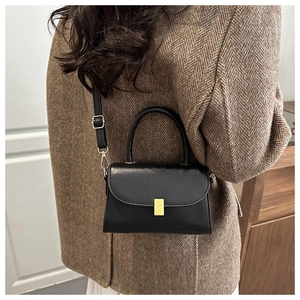 Detailed view of the black leather crossbody bag with a gold lock and handle