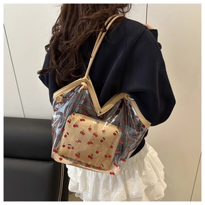 Detail of transparent PVC tote bag with cherry print and beige leather inner pouch
