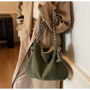 Detail of dark green corduroy tote bag with black and white striped woven strap handle