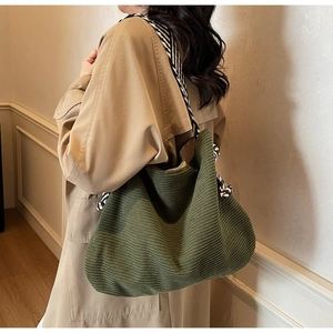 Détail du sac cabas en velours côtelé vert armée avec bandoulière large rayée noir et blanc