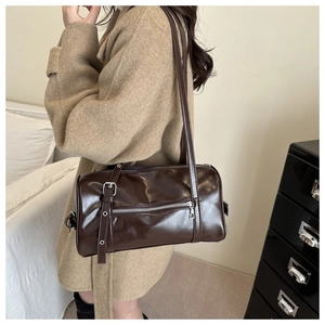 Détail d'un sac bowling marron foncé avec fermeture éclair argentée et fines lanières