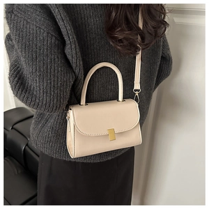 Close-up of cream square bag with gold buckle on gray sweater for detail view