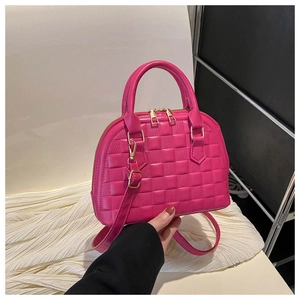 Detail of rose red shell bag featuring checkered texture and gold zipper hardware