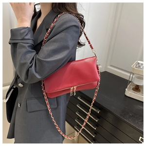 Detail of red pebbled leather crossbody bag featuring gold chain and double zipper design