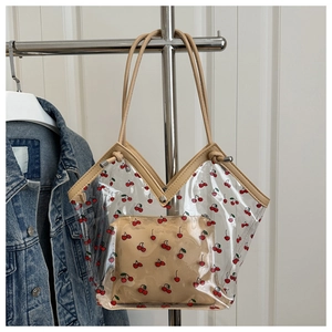 Close-up of transparent PVC tote bag with red cherry prints and matching inner pouch