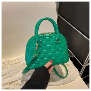 Close-up of bright green shell bag featuring embossed checkerboard texture and golden zipper