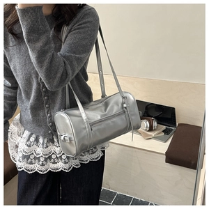 Vue détaillée du sac cylindrique argenté avec rivets et bandoulière réglable