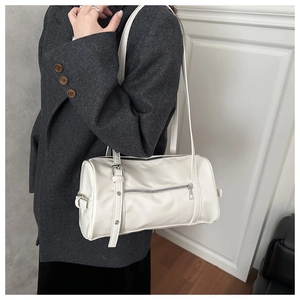 Gros plan d'un sac Boston blanc en cuir avec détails argentés sur un blazer gris