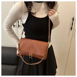 Brown lychee leather crossbody bag with chain strap and zipper detail on shoulder