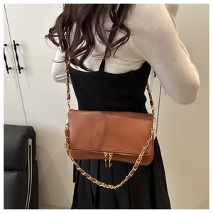 Detail of caramel brown lychee leather shoulder bag with decorative metal zippers