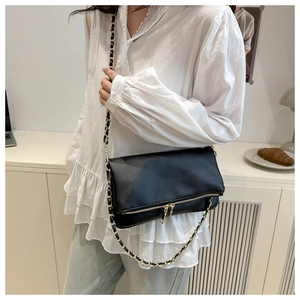 Detail of black pebbled leather chain bag featuring gold zippers and stylish flap design
