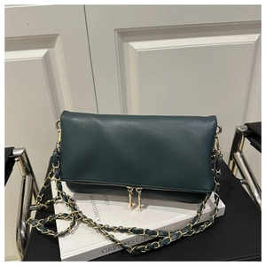 Detail of teal pebble leather shoulder bag with gold dual zippers and chain strap