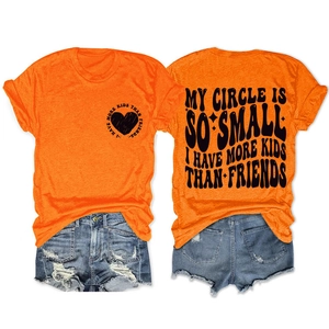 Détail du t-shirt orange avec imprimé cœur et du short en jean avec finitions effilochées